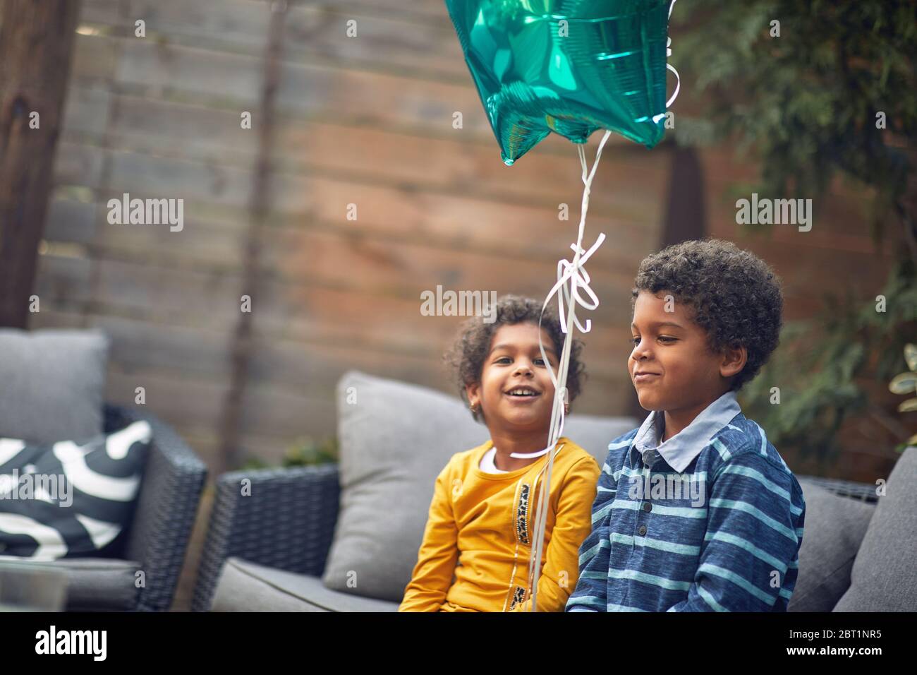 Petit frère afro-américain et sœur assis ensemble à l'extérieur et jouer avec le ballon. Banque D'Images
