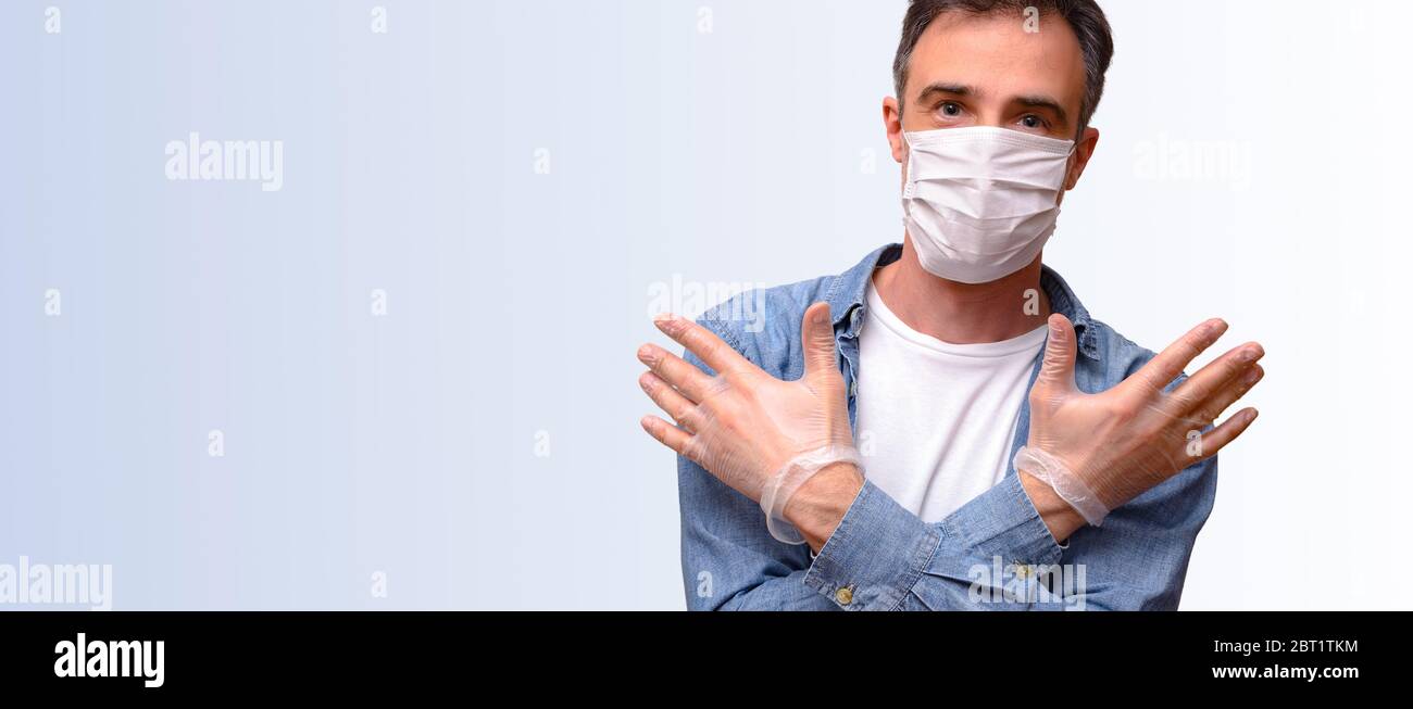 Homme fourni avec des éléments de protection personnelle comme le masque et les gants vêtus de vêtements décontractés et fond bleu dégradé Banque D'Images