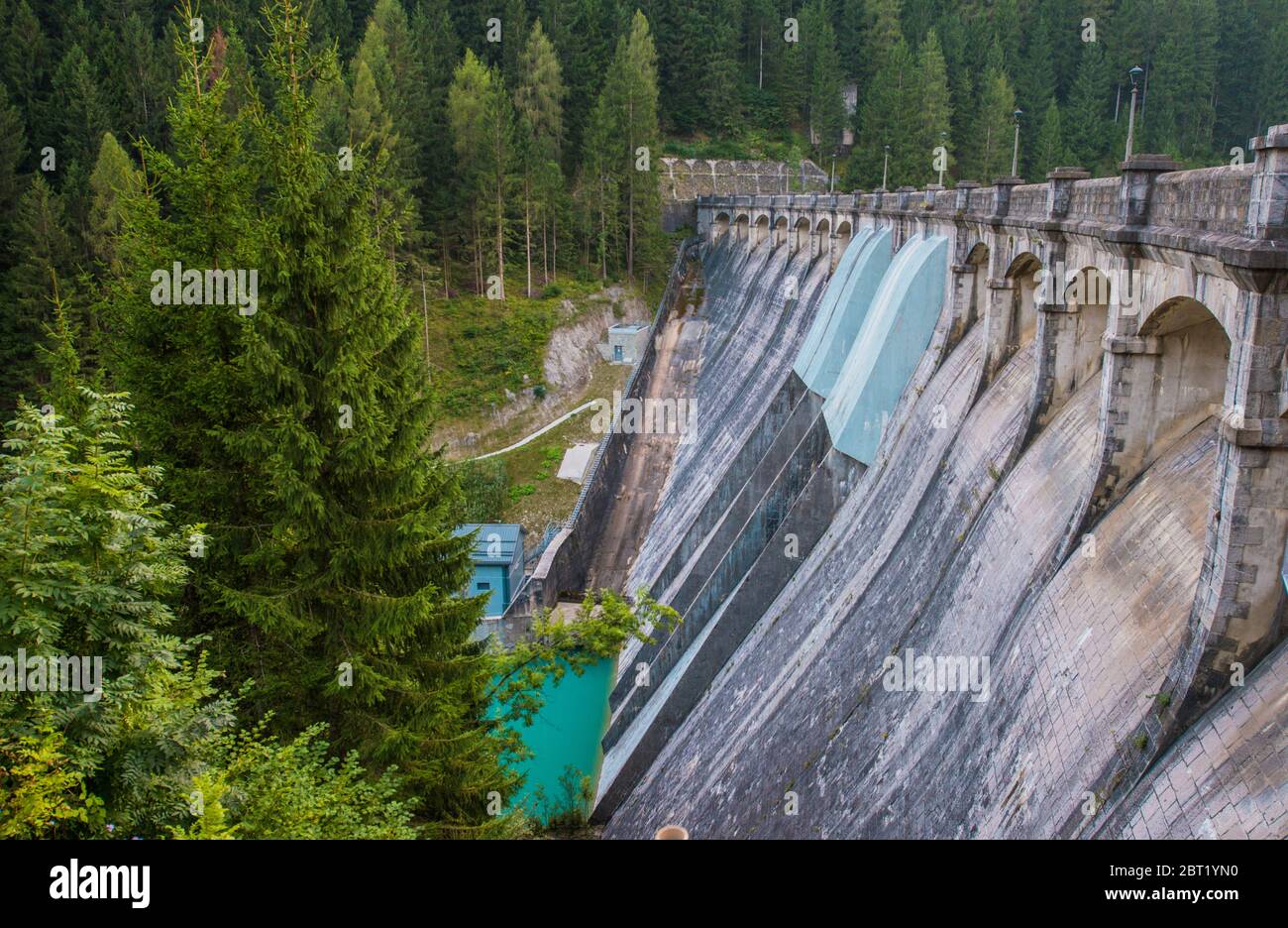 Vue sur l'Italien Auronzo Di Cadore énorme barrage avec l'eau turquoise en dessous et des pins autour. Banque D'Images