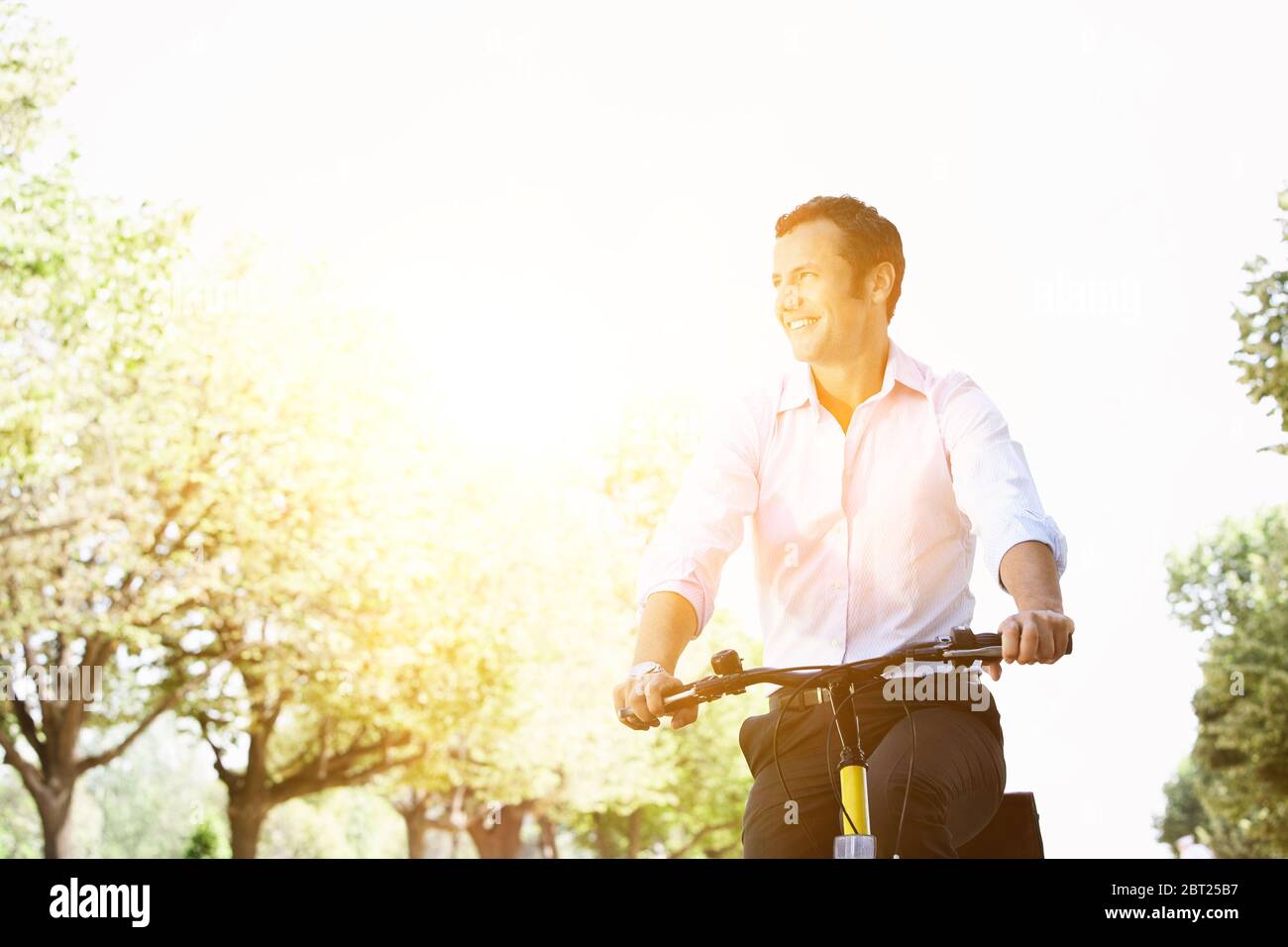 Homme d'affaires à vélo pendant la journée ensoleillée d'été dans le parc Banque D'Images