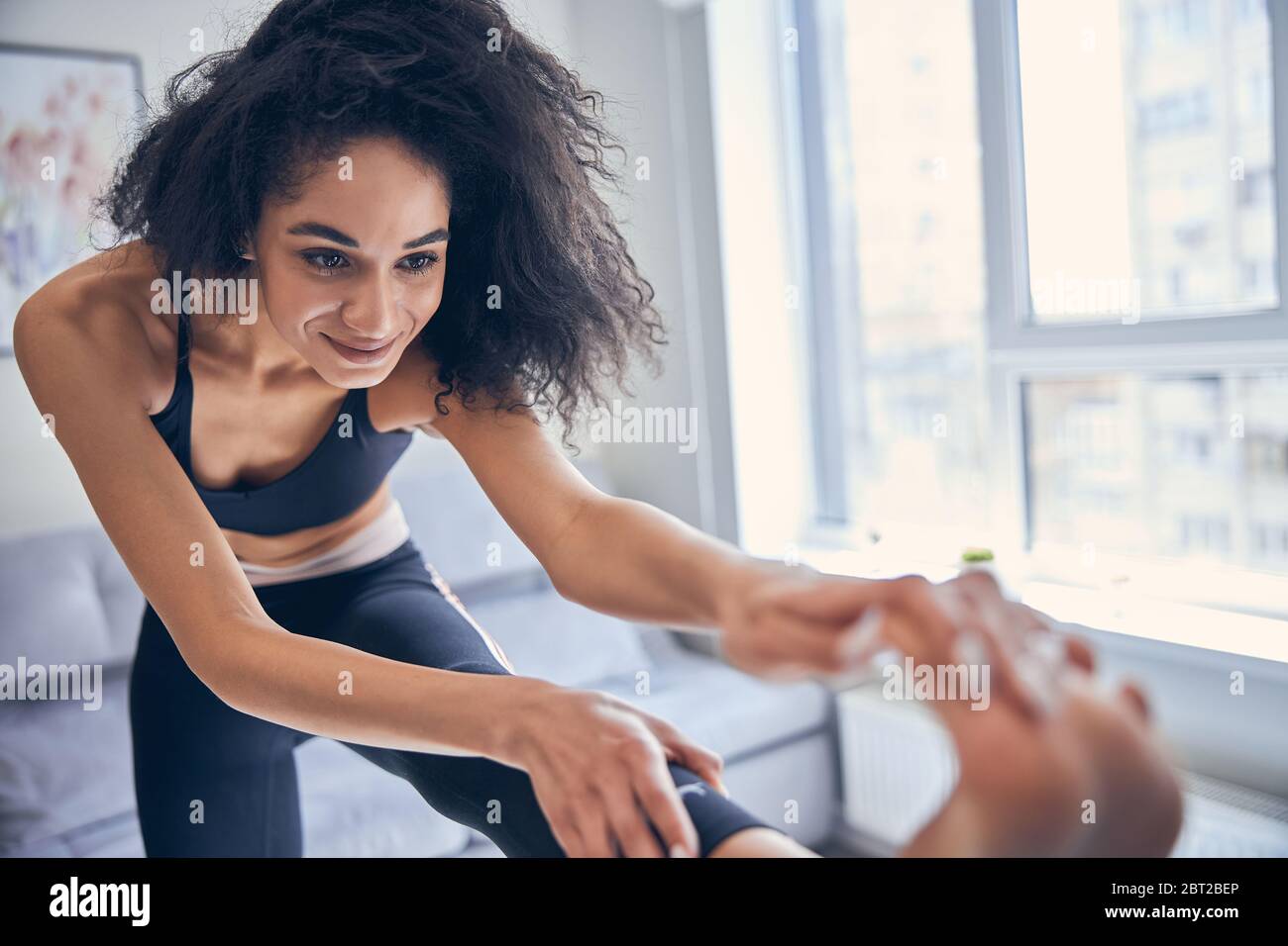 Femme souriante pratiquant le yoga à la maison Banque D'Images