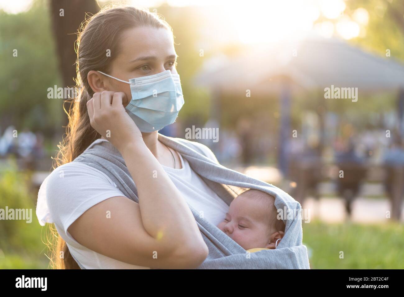 Maternité, soins, nourrissons, été, coronavirus et concept de quarantaine - jeune belle mère avec un nouveau-né dans une élingue marche dans un médical Banque D'Images