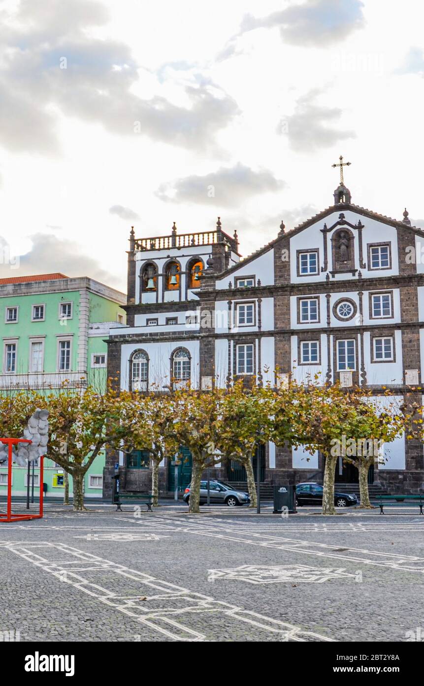 Ponta Delgada, Açores, Portugal - 12 janvier 2020 : place pavée dans le centre historique de la ville portugaise. Maisons historiques traditionnelles. Coucher de soleil avec nuages. Photo verticale. Banque D'Images