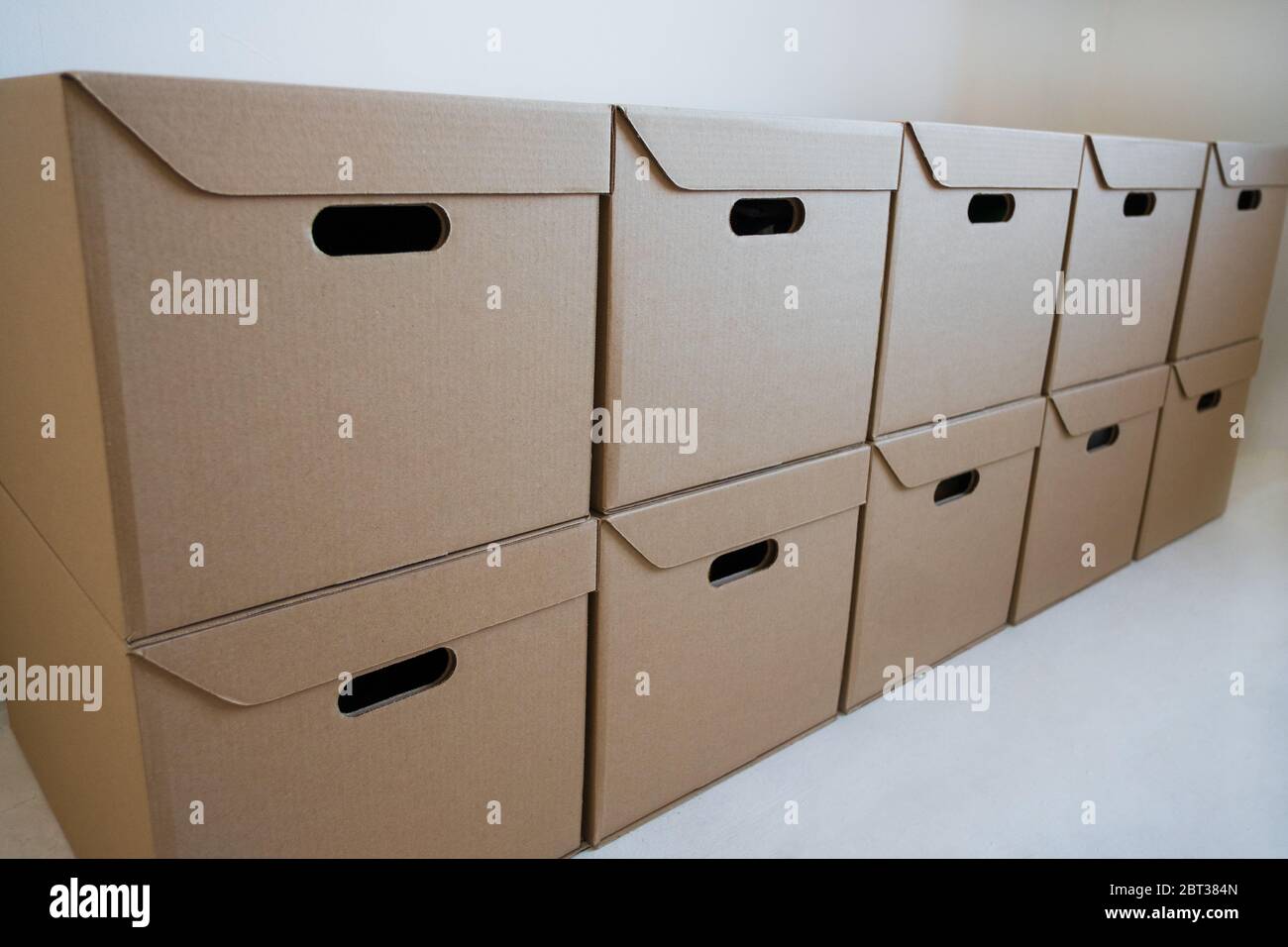 Gros plan - boîtes en carton pour le stockage qui sont bien empilées contre un mur blanc. Concept de livraison. Banque D'Images