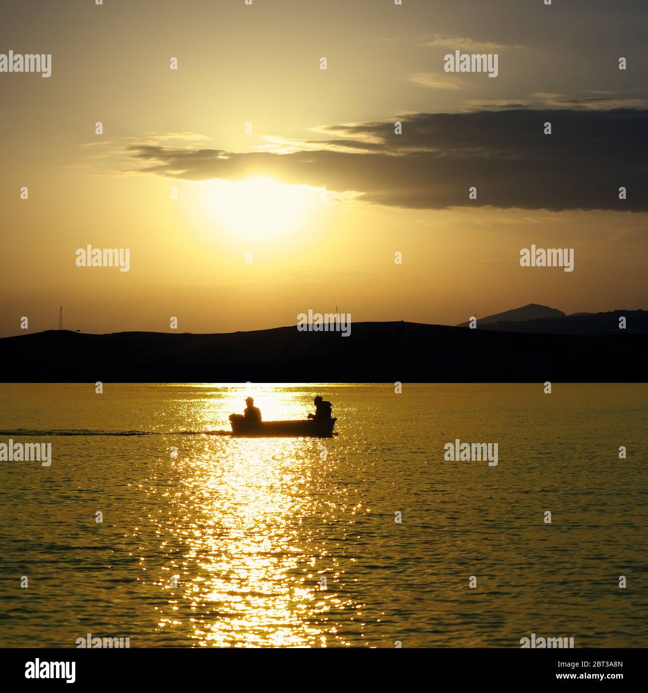 mer de Sicile au coucher du soleil doré, bateau silhouette et deux pêcheurs Banque D'Images