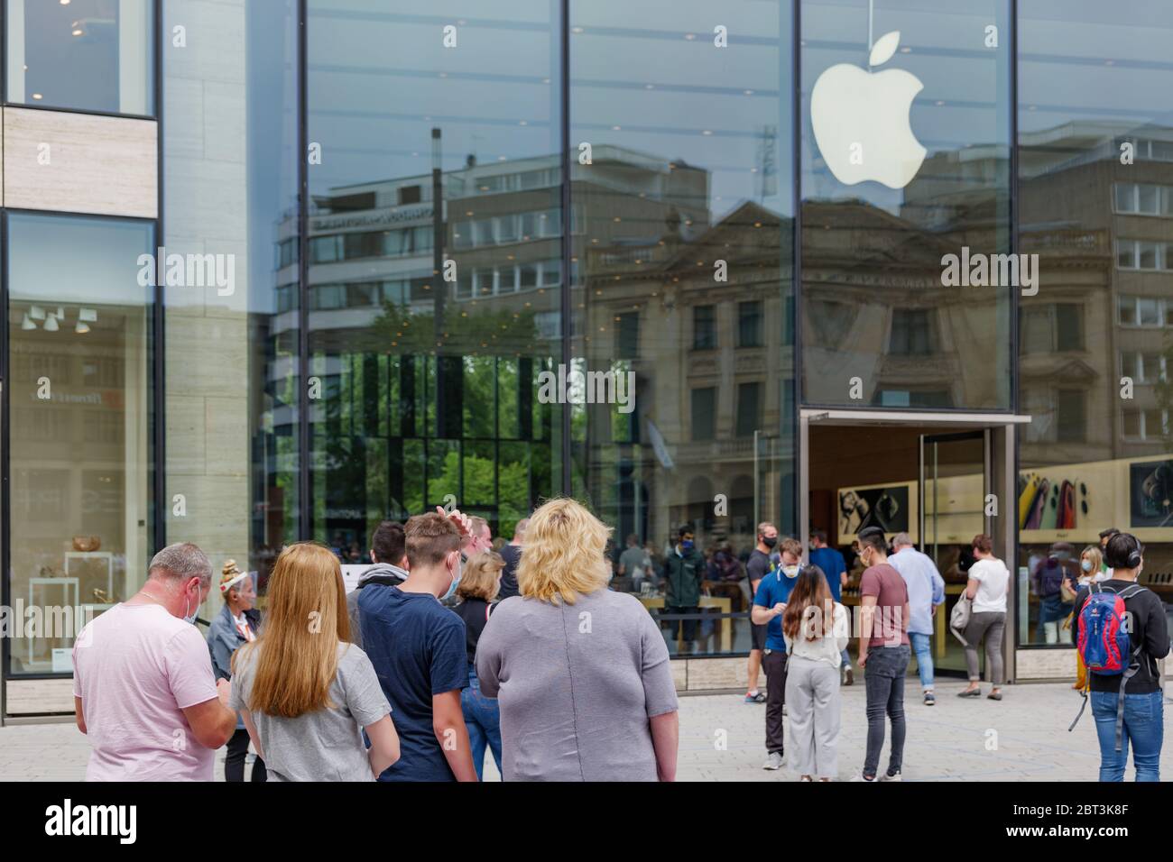 Les personnes avec masque de couverture de visage font la queue et attendent à l'extérieur de l'Apple Store sur Shadowplatz pendant les règlements de distanciation sociale et de quarantaine pour COVID-19. Banque D'Images