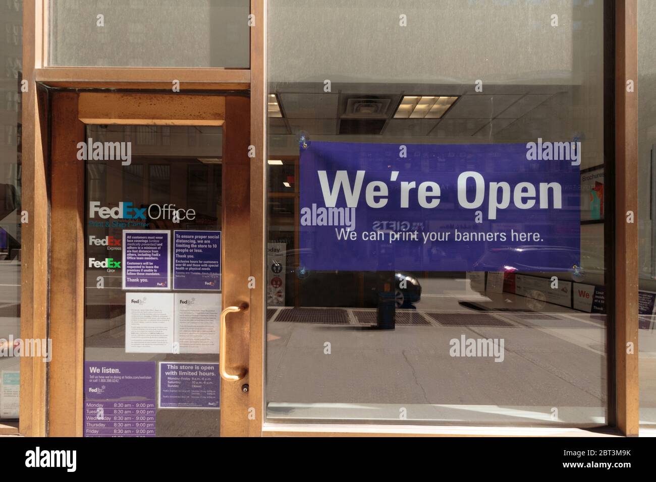 Un magasin FedEx informe le public qu'il est ouvert aux affaires avec un panneau violet bien en vue indiquant que nous sommes ouverts pendant la pandémie du coronavirus ou du covid-19 Banque D'Images