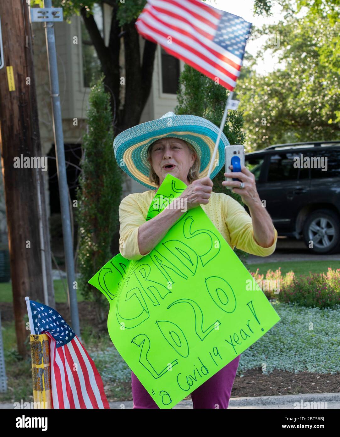 Les résidents applaudissent tandis que les diplômés du secondaire défilent dans leur quartier d'Austin, au Texas, à la suite de la pandémie COVID-19 qui a raccourci l'année scolaire et forcé l'annulation des cérémonies traditionnelles de commencement en personne. Banque D'Images