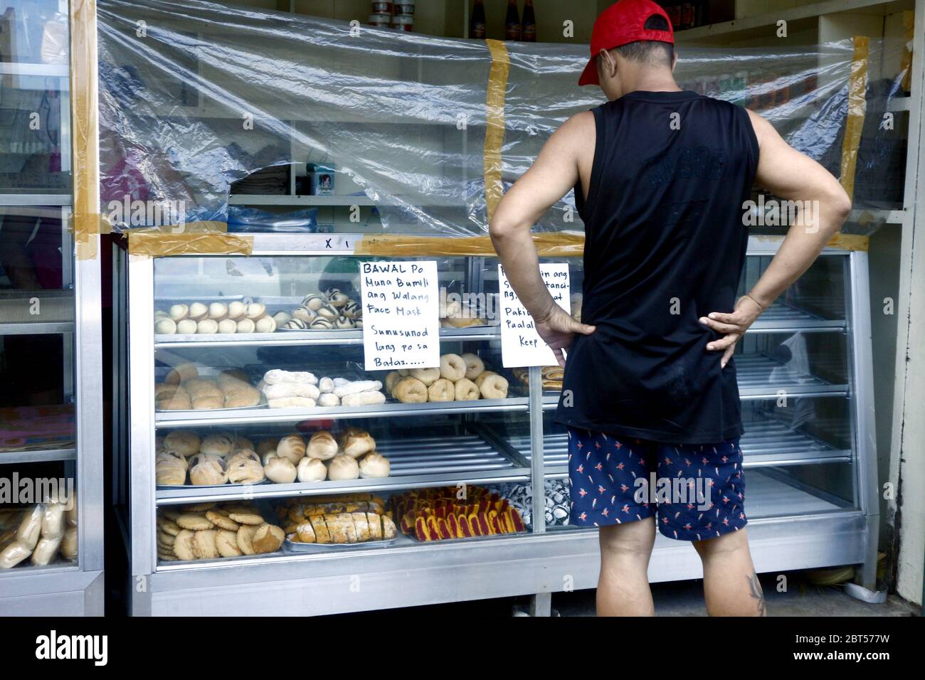 Antipolo City, Philippines - 21 mai 2020 : les clients achètent dans une boulangerie avec barrière plastique comme protection pendant l'épidémie de virus Covid 19. Banque D'Images