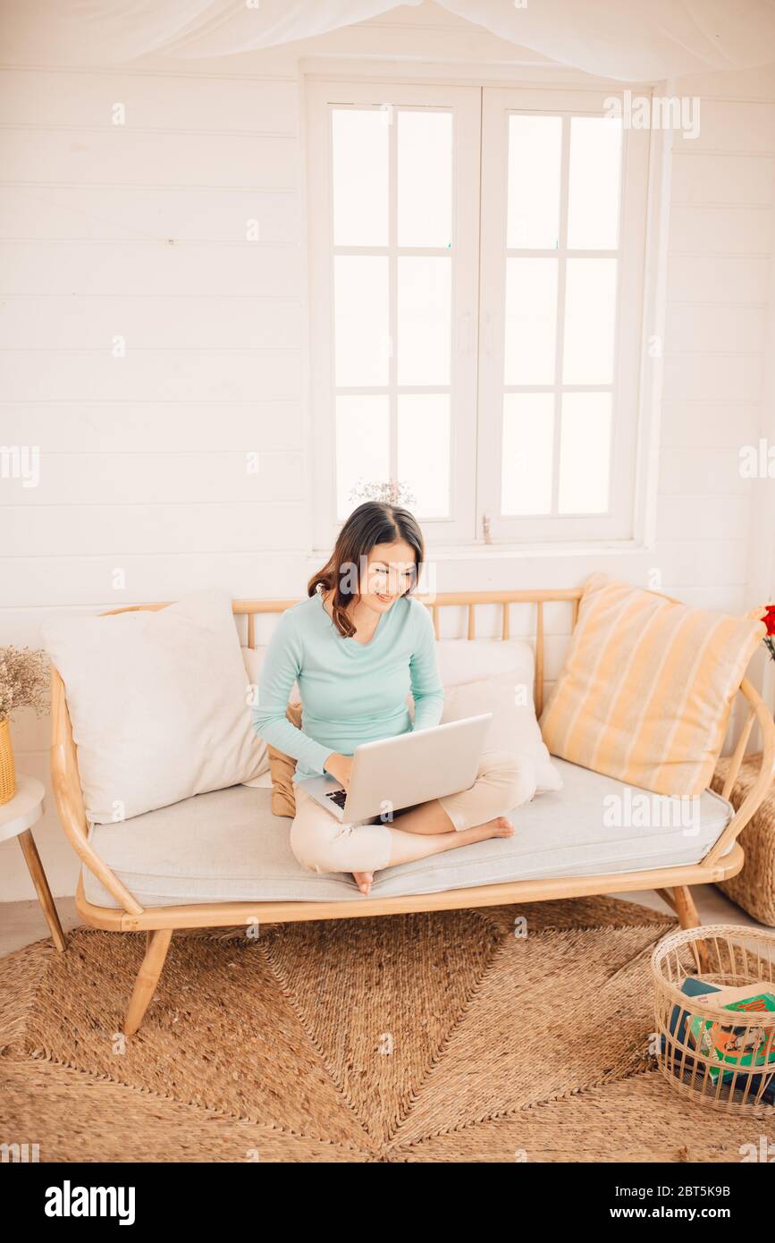 Young Asian woman working on laptop at home. Banque D'Images