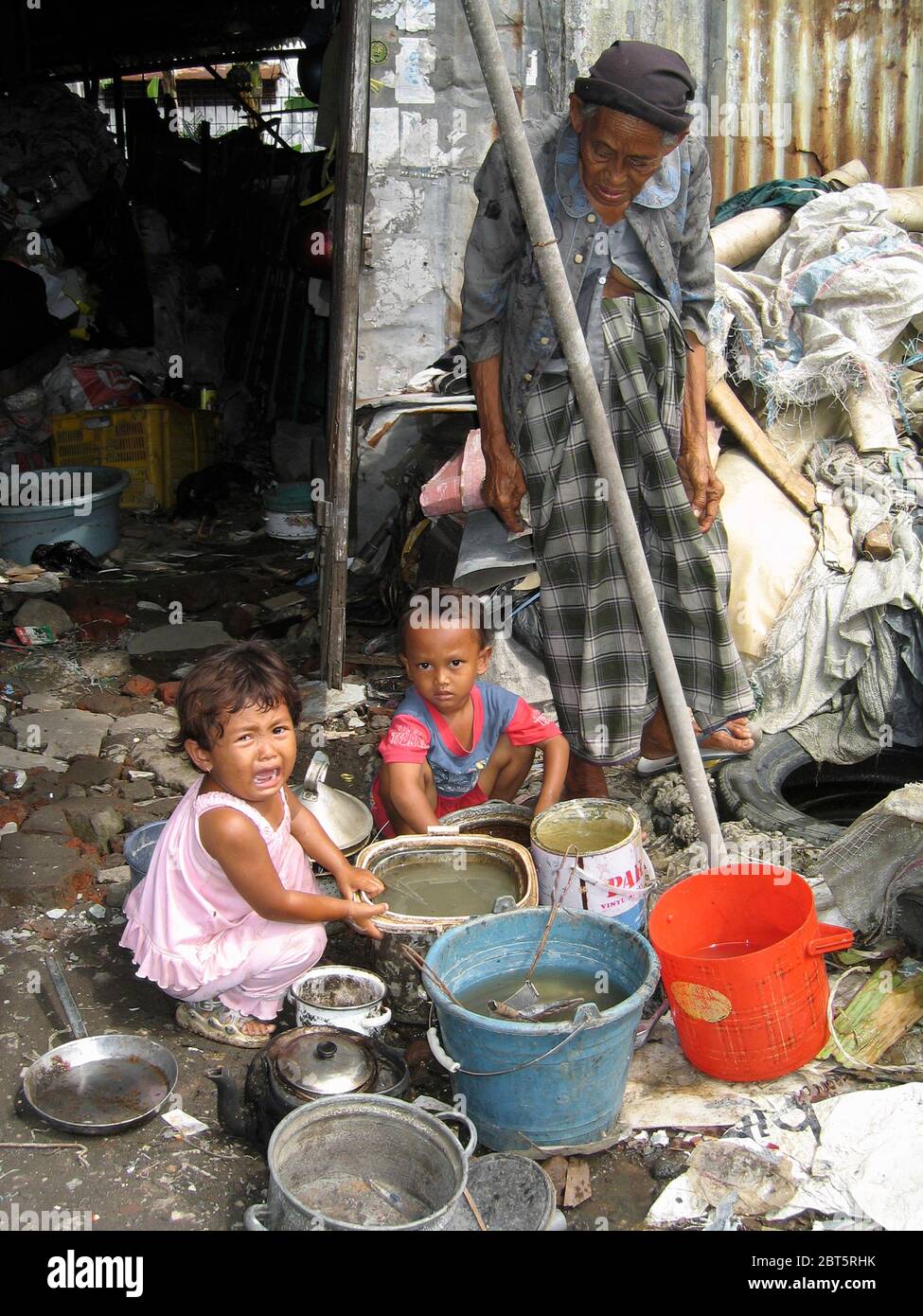 vieille dame avec de petits enfants à la maison crasseuse de déchets crasseux dans le bidonville à côté de la rivière kalima surabaya java indonésie Banque D'Images