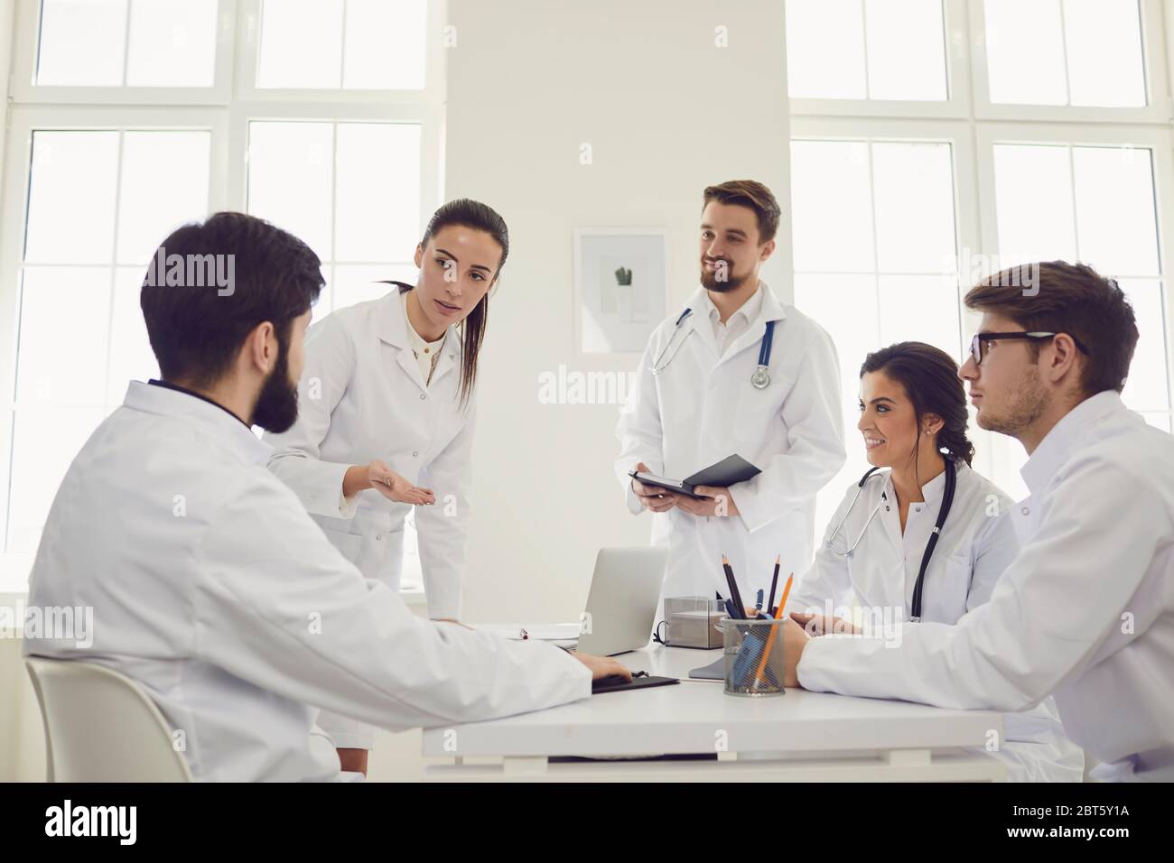 Un groupe de médecins praticiens en réunion discute du diagnostic d'un patient assis à un bureau dans un cabinet clinique. Médecins confiants à la conférence ta Banque D'Images