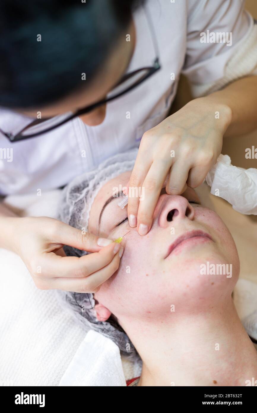 Le soin du visage dans un spa par une esthéticienne féminine. Une esthéticienne féminine nettoie la peau d'une femme dans le centre de spa. Extraction de points noirs ou de gros points Banque D'Images