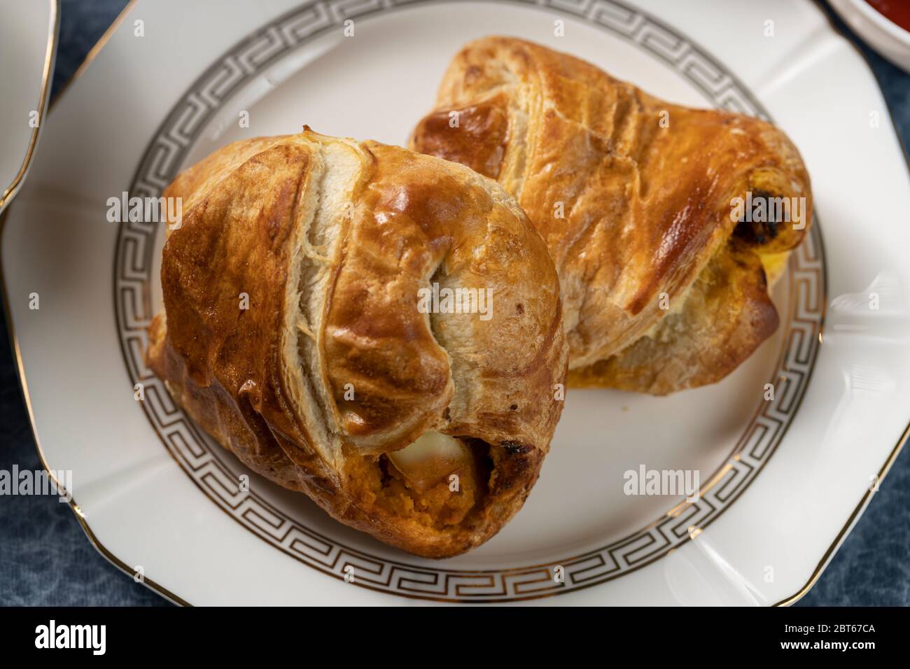 Croustillant d'oeufs sur un plat blanc avec sauce tomate, chutney vert, tasse de thé sur une table bleue Banque D'Images