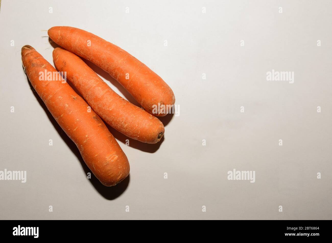 Photo aérienne d'un groupe de trois carottes fraîches sur fond blanc Banque D'Images