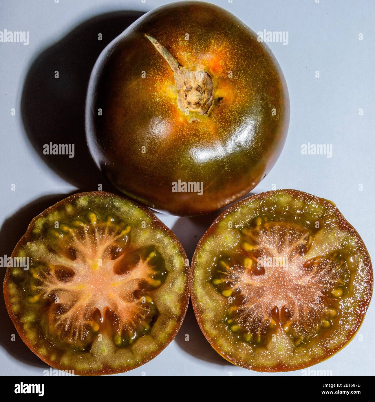 Une paire de tomates fraîches de Kumato ouvre en deux sur fond blanc Banque D'Images