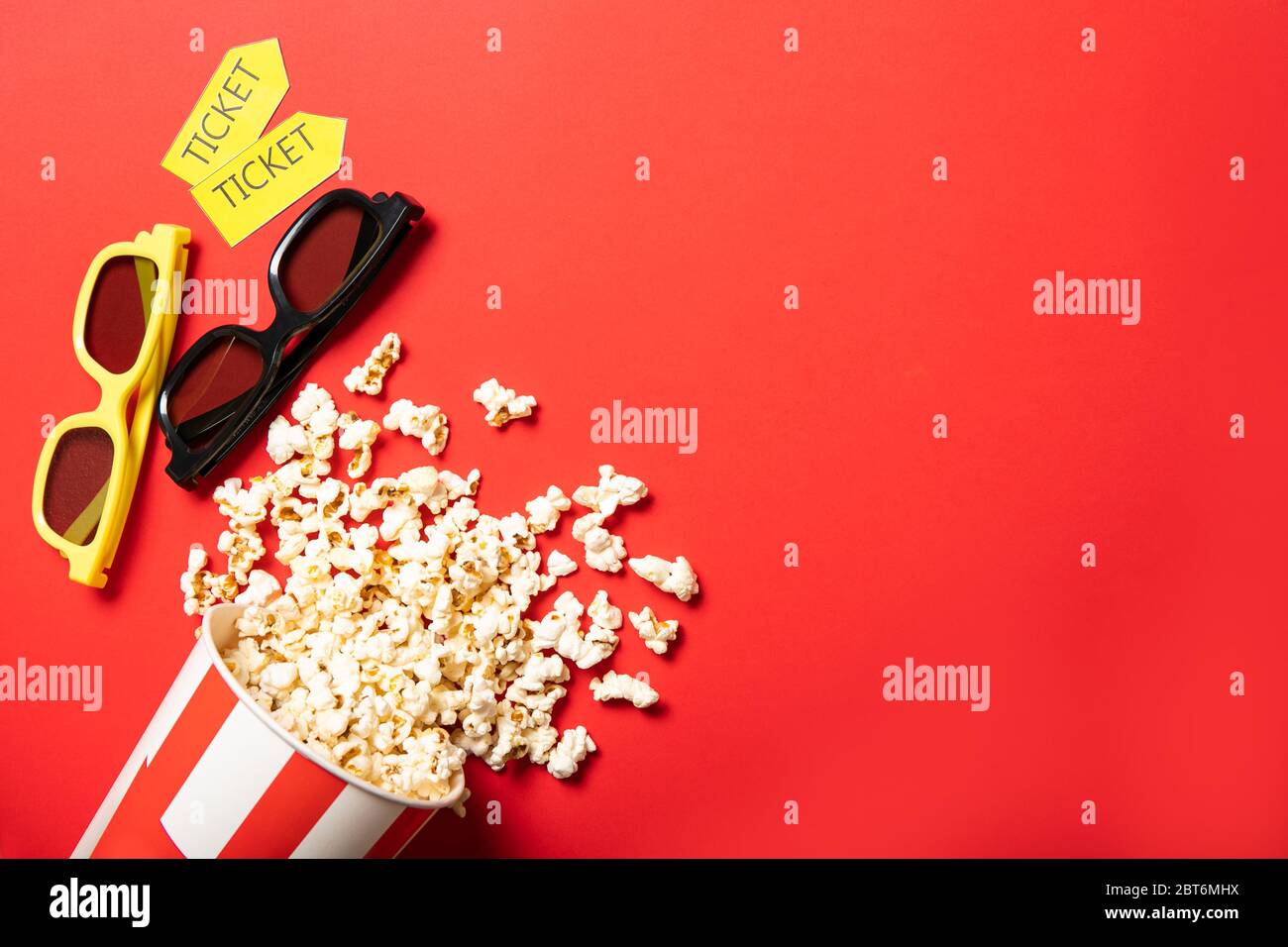 Gobelet en papier avec pop-corn sur fond rouge. Points et billets de cinéma Banque D'Images