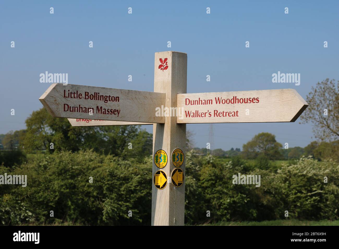 Panneau en bois National Trust indiquant les directions vers les maisons à bois Little Bollington, Dunham Massey et Dunham avec des symboles pour la route Bollin Banque D'Images