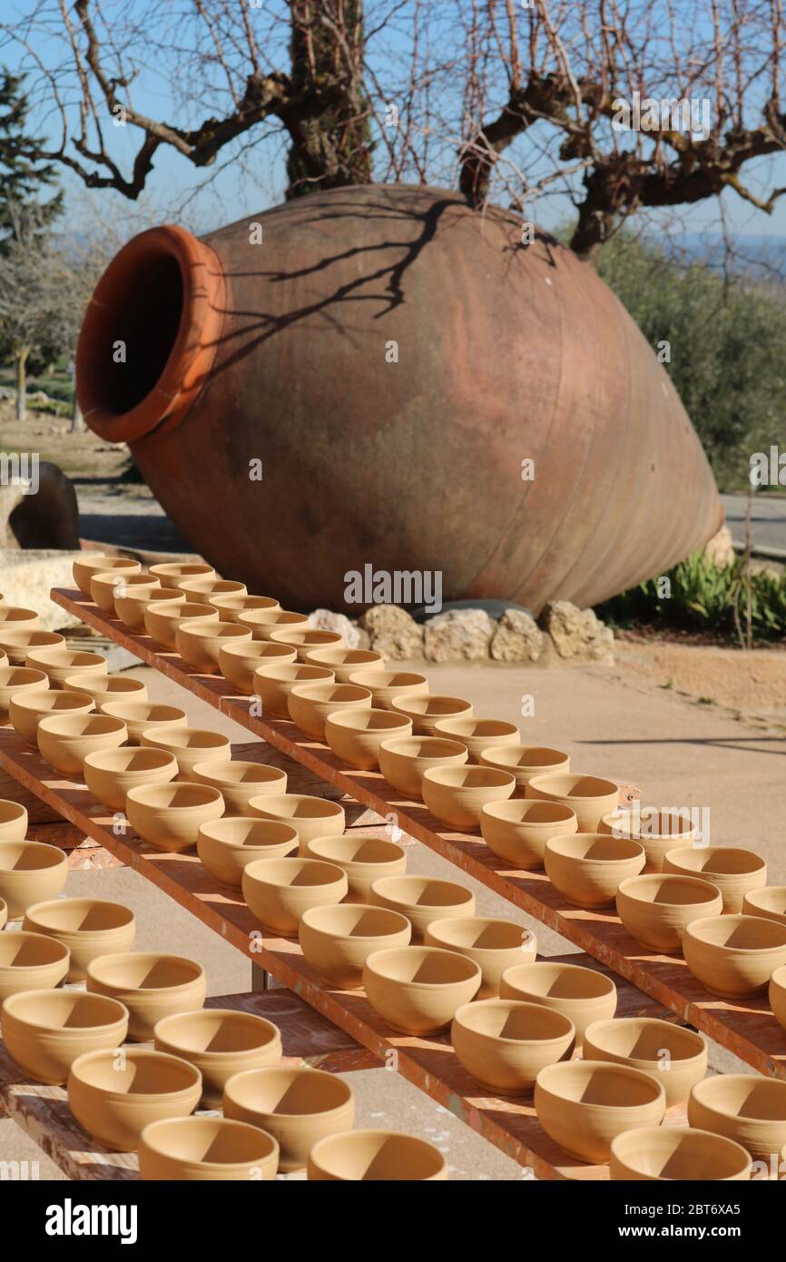 Amphore géante en terre cuite avec des rangées de bols en poterie non émaillée qui sèchent au soleil en face de lui en Catalogne Banque D'Images