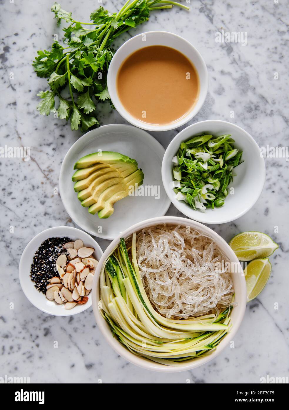 Ingrédients pour plat asiatique de nouilles de riz avec avocat, persil, légumes, amandes et graines de sésame Banque D'Images