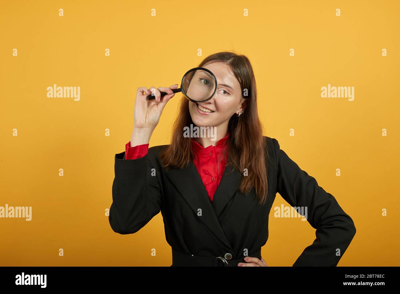 Femme souriante tient la loupe à la main et regarde avec l'œil. Scientifique Banque D'Images