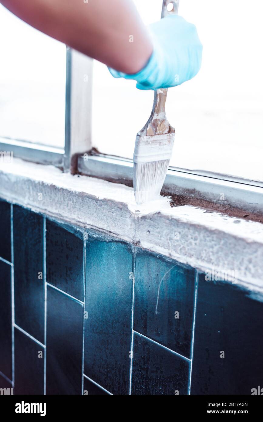 Mains en gants peignant un mur blanc Banque D'Images