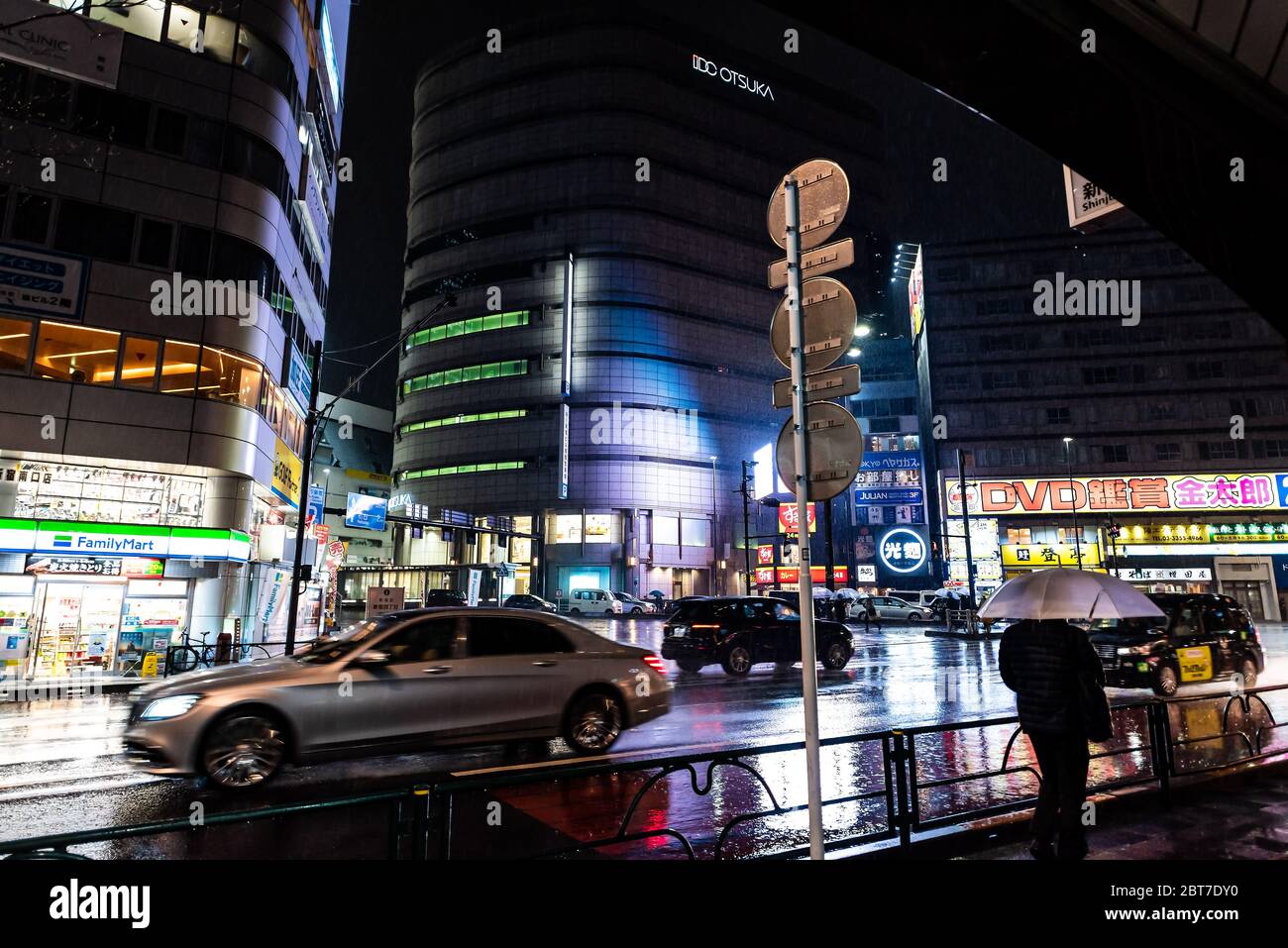 Tokyo, Japon - 1er avril 2019 : ville du centre-ville de Shinjuku, à proximité des voitures de gare dans la circulation et la pluie avec des personnes marchant avec des parasols et des mouvements flous Banque D'Images