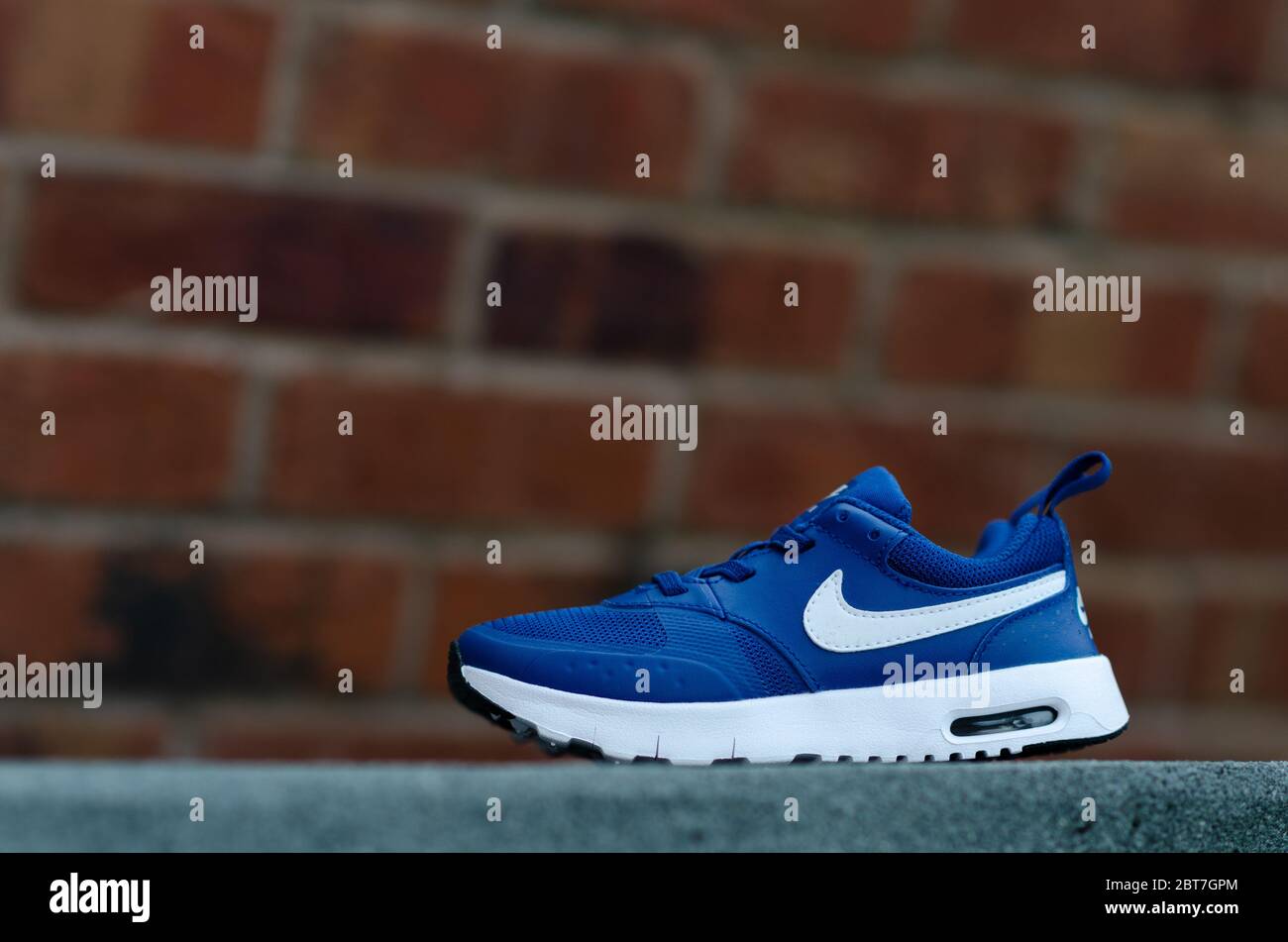 La photo en gros plan de la paire de baskets Nike Air bleues pour enfant. Le mur de briques est sur l'arrière-plan. Le champ de vision peu profond a été utilisé pour l'imagerie. Banque D'Images