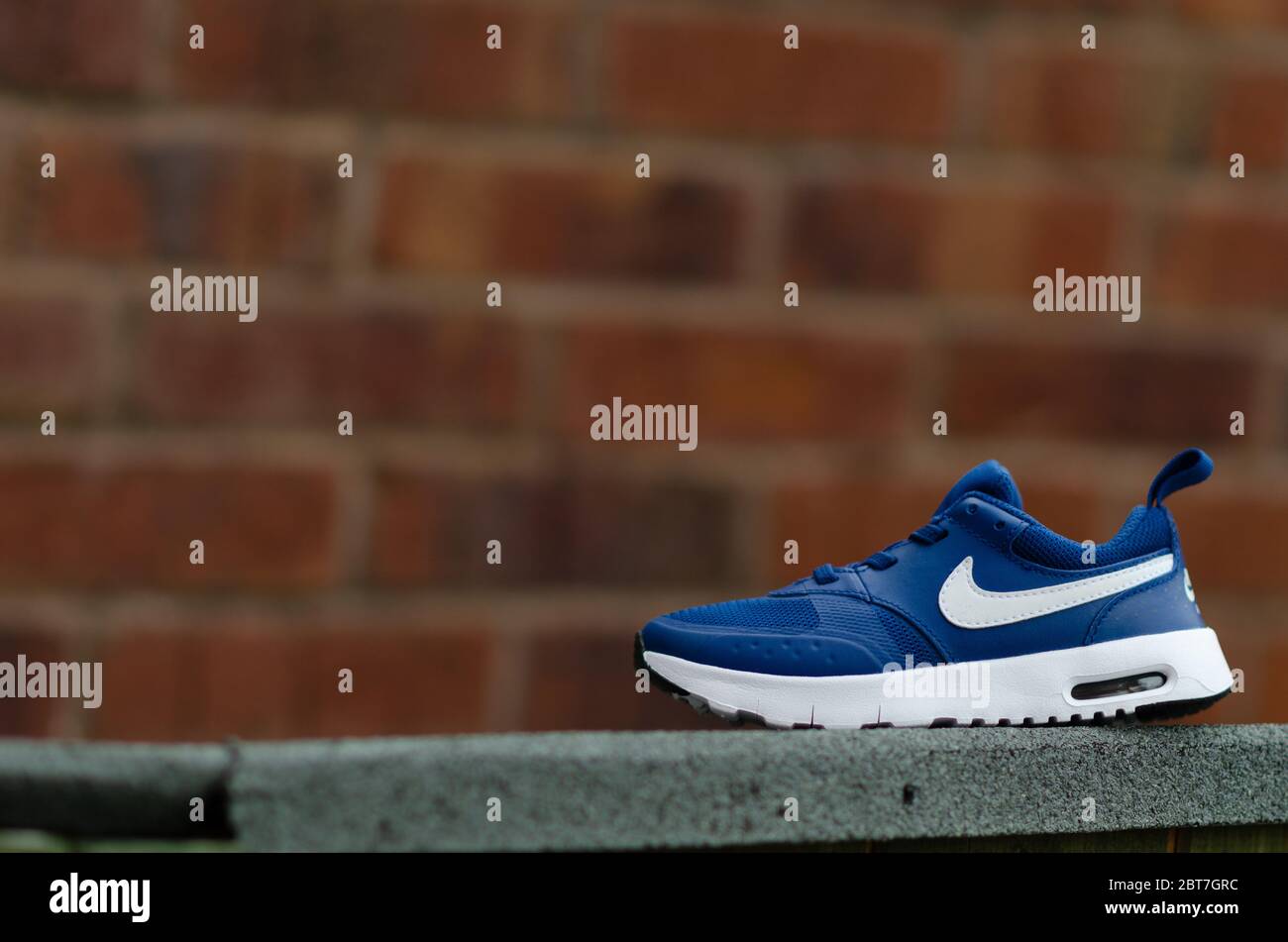 La photo en gros plan de la paire de baskets Nike Air bleues pour enfant.  Le mur de briques est sur l'arrière-plan. Le champ de vision peu profond a  été utilisé pour