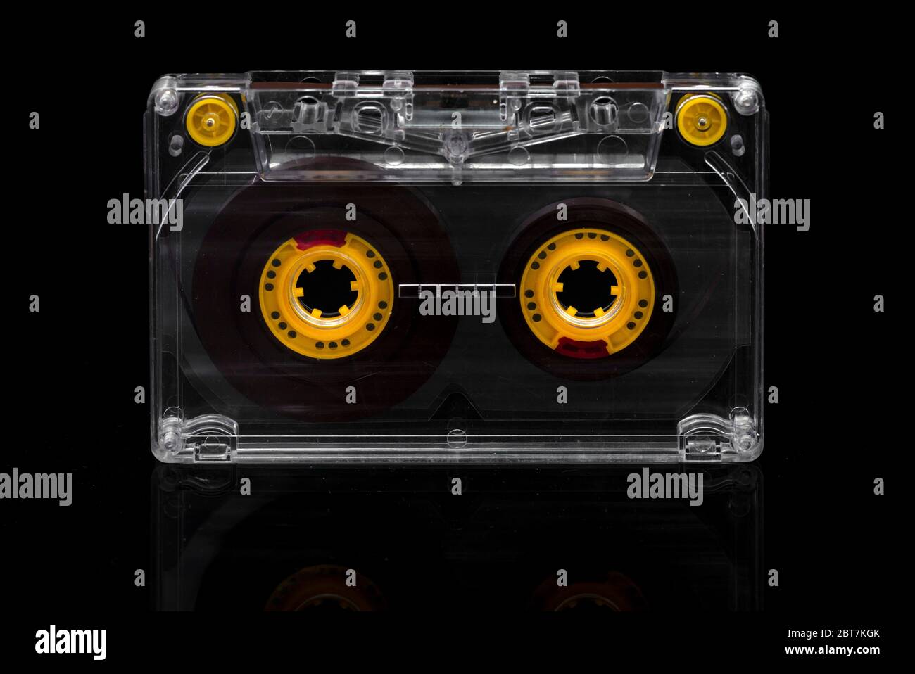Cassette audio avec bobines de ruban jaune et guides de ruban sur fond noir Banque D'Images