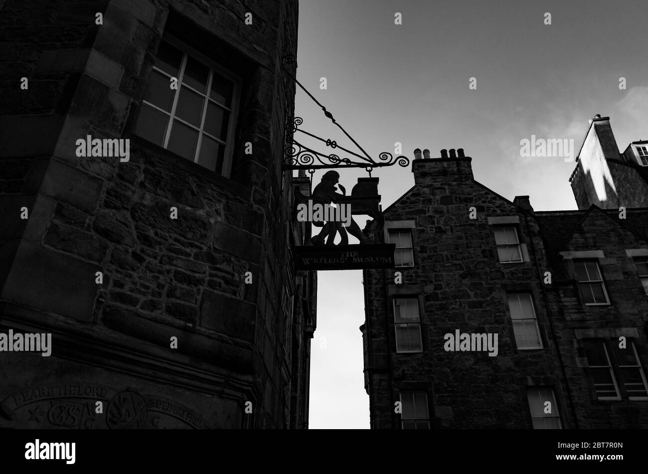 Signe de l'homme au bureau devant le Writers Museum Edinburgh avec des bâtiments en arrière-plan. Prise de vue spectaculaire en noir et blanc. Banque D'Images