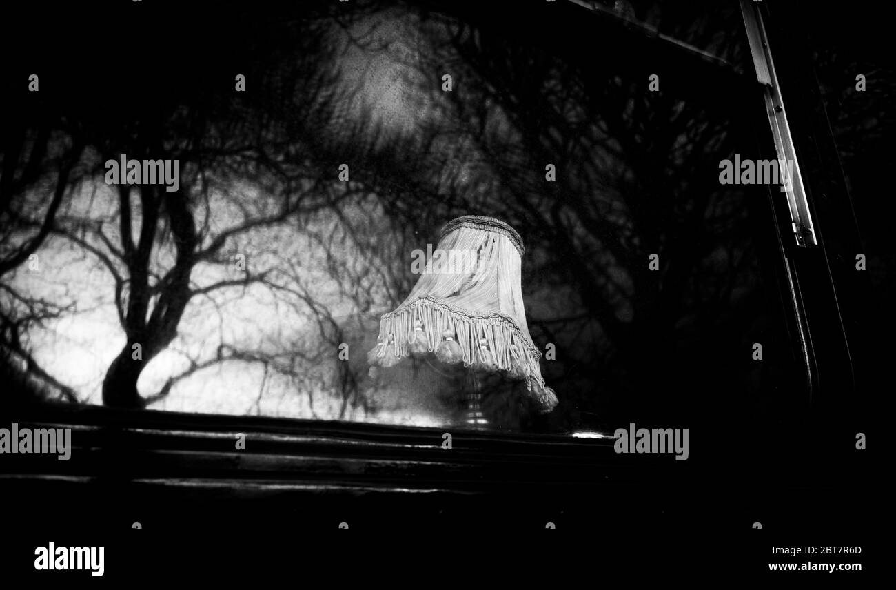 Lampe à l'ancienne à la fenêtre du bus fantôme garée à Édimbourg pendant le confinement 2020 avec des reflets d'arbres dans les fenêtres. Noir et blanc spectaculaire. Banque D'Images
