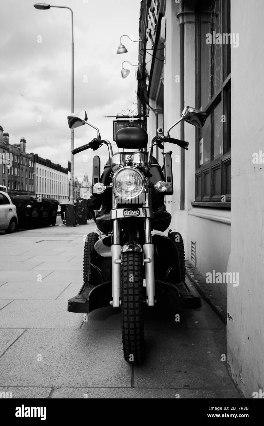 Scooter de motability original à l'extérieur du Windsor Pub, Édimbourg. Photographie de rue, photo en noir et blanc. Banque D'Images