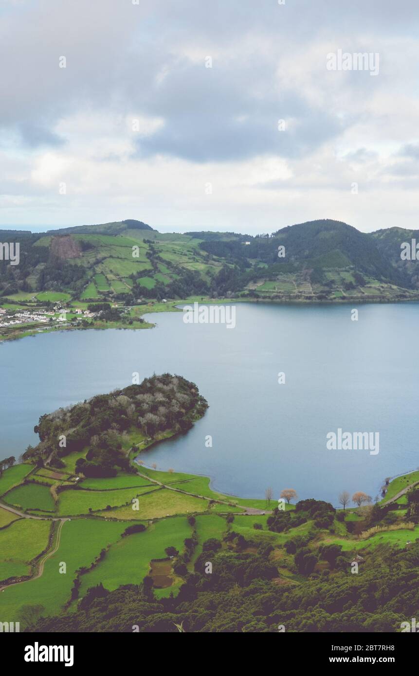 Vue imprenable sur le Lagoa Azul et le village de Sete Cidades depuis le point de vue de Miradouro do Cerrado das Freiras aux Açores, au Portugal. Lacs entourés de champs verts et de forêts. Photo verticale. Banque D'Images