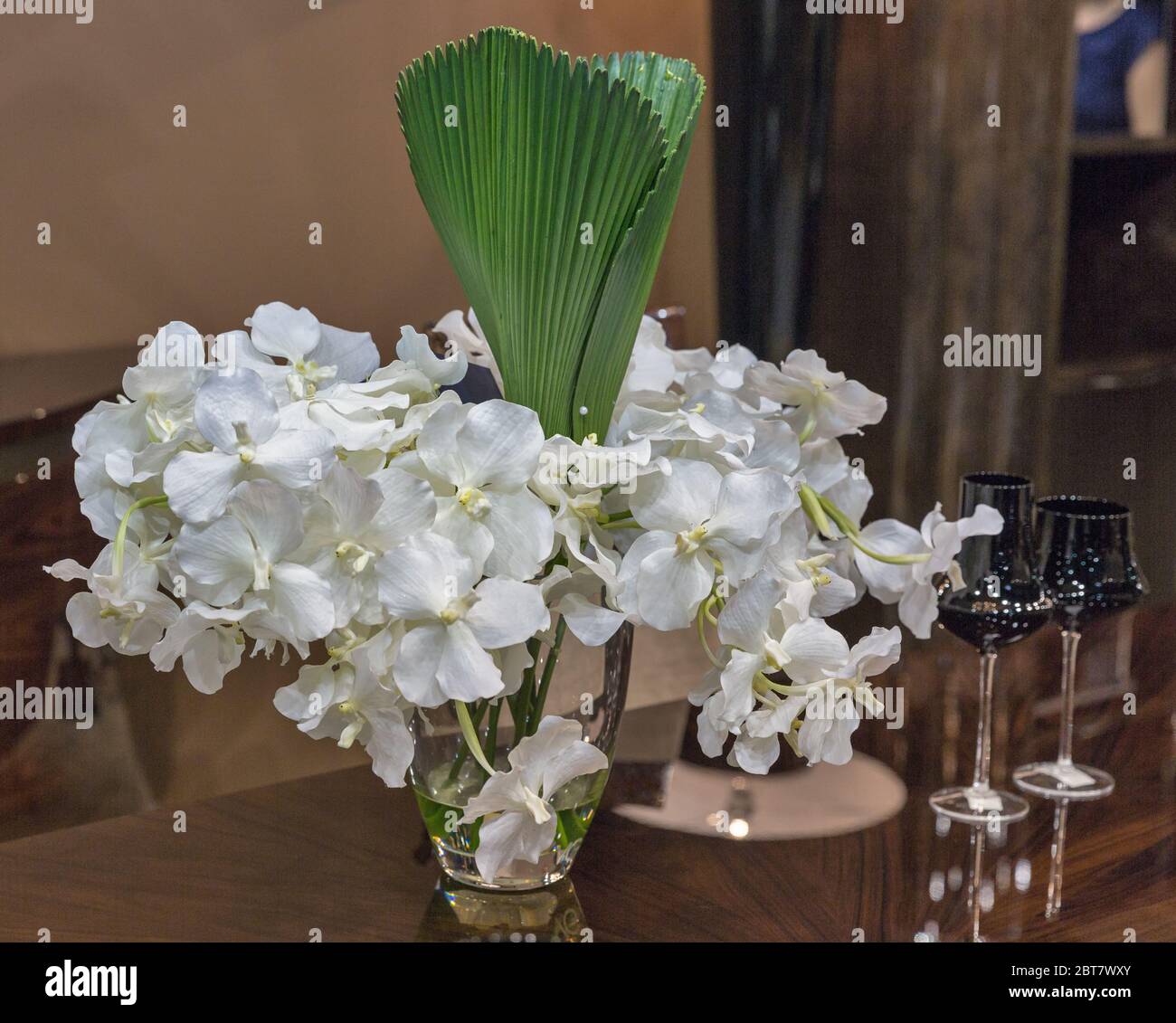 ?loseup de fleurs d'orchidées blanches arrangement de bouquet dans vase en verre avec feuille de palmier à l'intérieur Banque D'Images