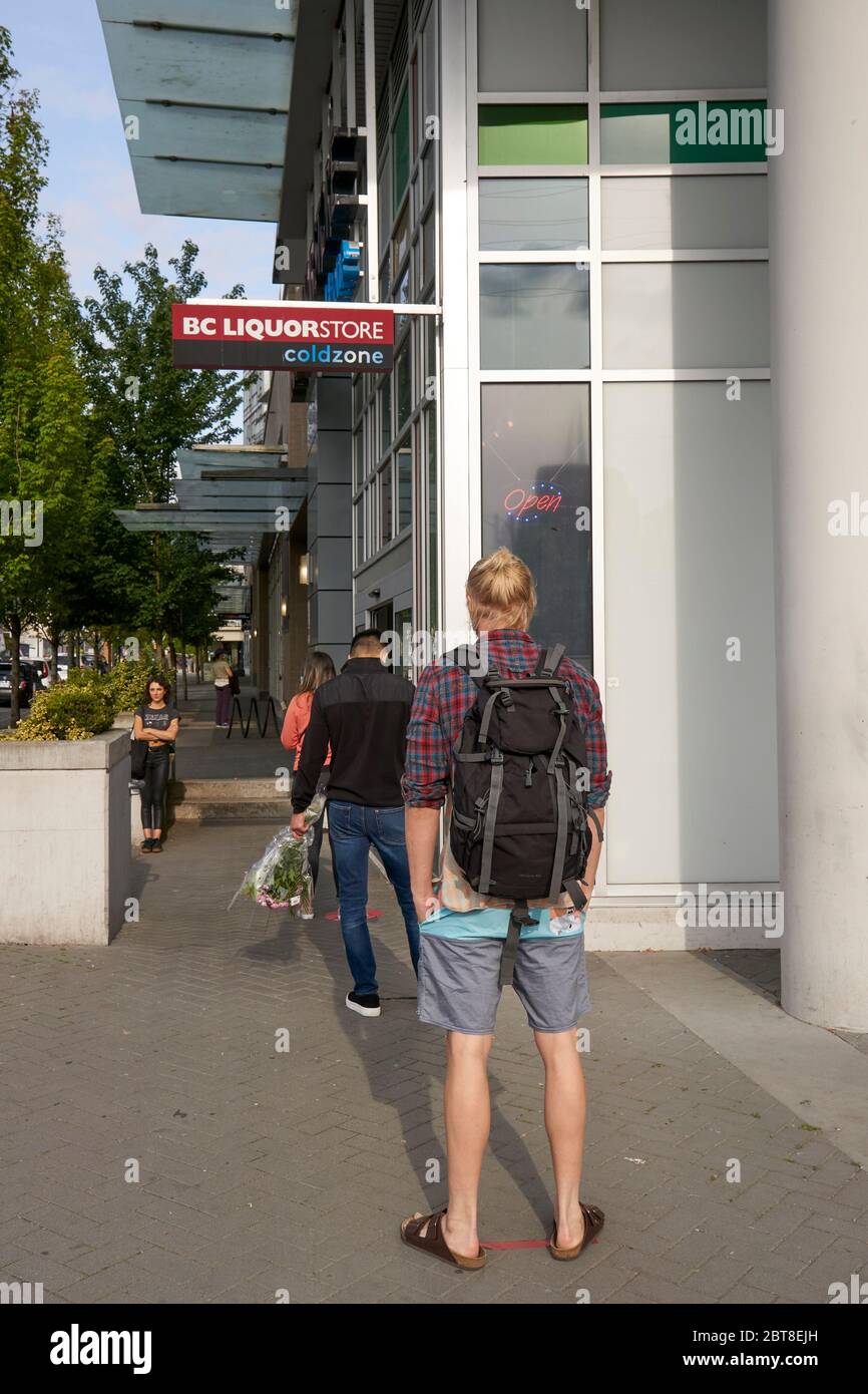 Vancouver, Canada, le 23 mai 2020. Les gens pratiquent la distanciation sociale tout en se faisant la queue pour entrer dans un magasin de boissons alcoolisées de la Colombie-Britannique pendant la pandémie de COVID-19 . Banque D'Images