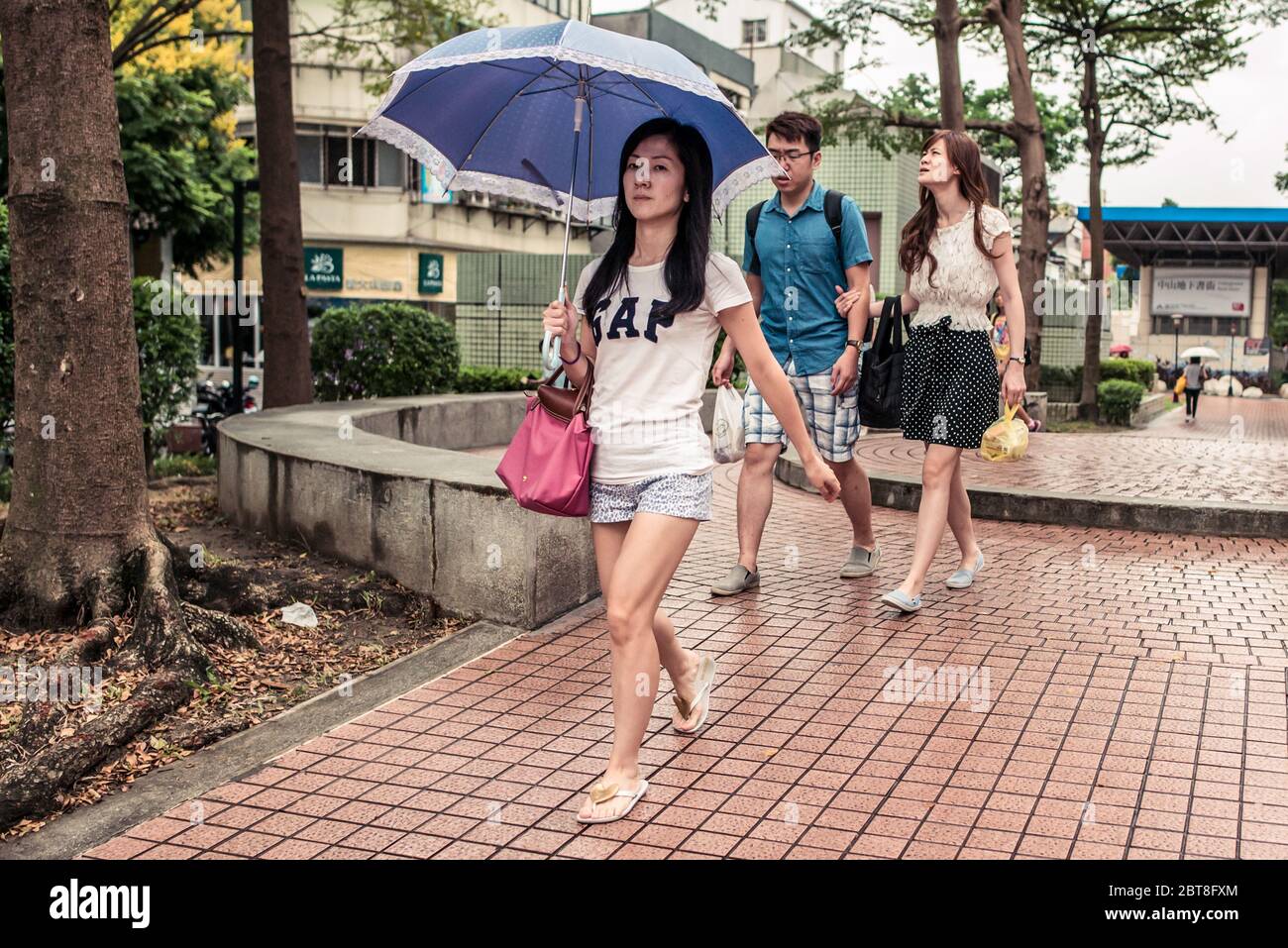Taipei / Taïwan - 12 décembre 2018: Jeune femme taïwanaise avec CHEMISE  BLANCHE GAP marchant portant un parapluie bleu pendant la journée  ensoleillée dans le parc Photo Stock - Alamy
