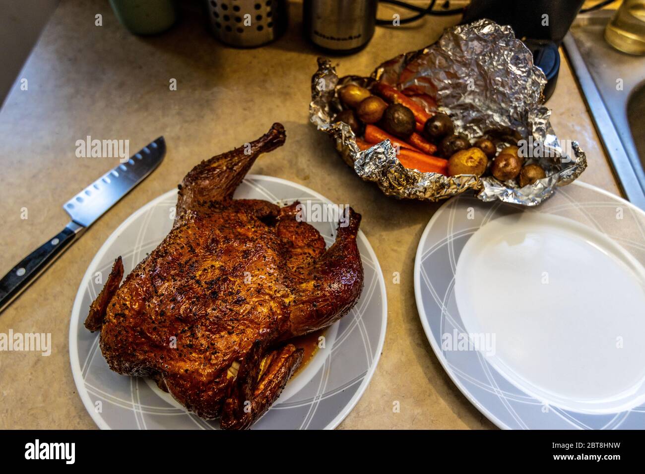 Un poulet entier fumé avec de la bois de pomme sur une bouilloire Weber  barbecue avec un paquet de pommes de terre et de carottes Photo Stock -  Alamy