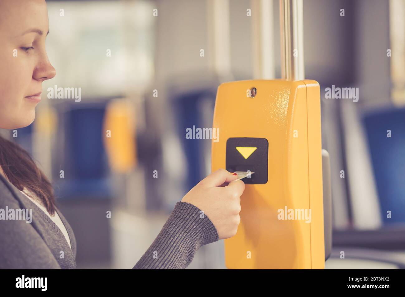 La main jeune femme insère le billet de bus dans le validateur, validant et ticking, le concept de transport public Banque D'Images