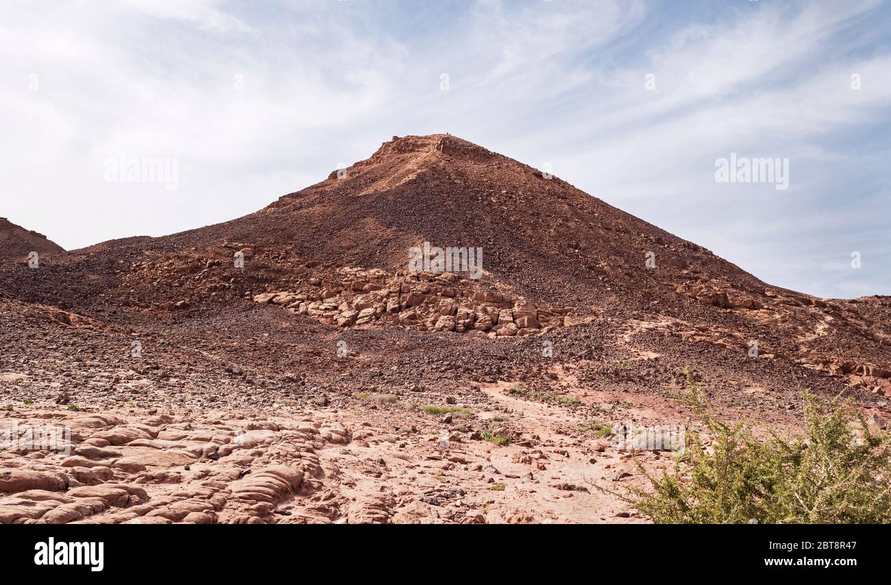 sentier de randonnée sur une colline de harut qui est une formation de grès en forme de cône avec une patine de vernis de désert couvrant les pierres à la surface Banque D'Images
