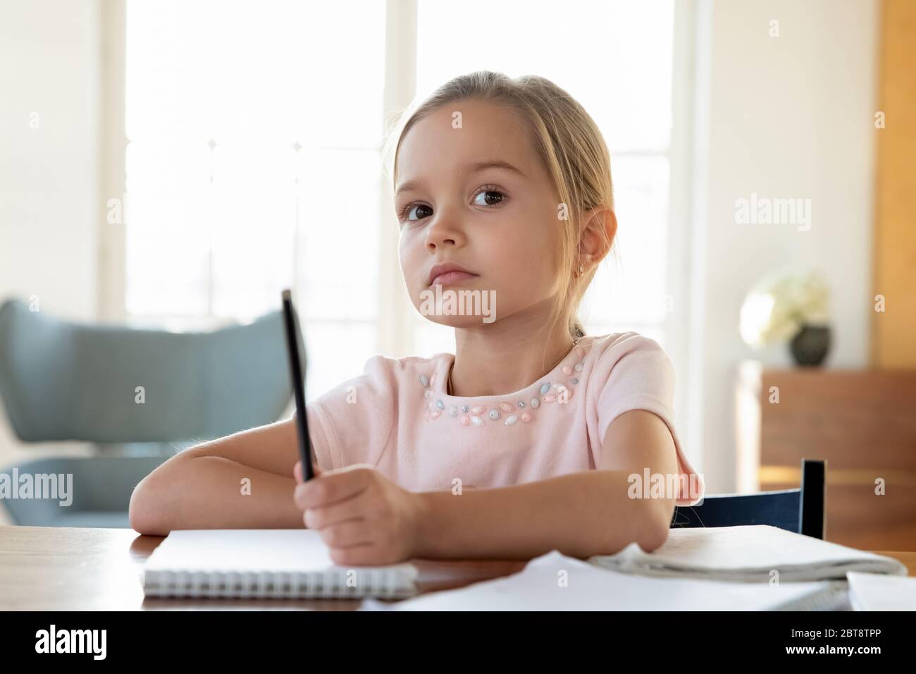 Petite fille ennuyeuse regarder dans la distance distraite d'étudier Banque D'Images