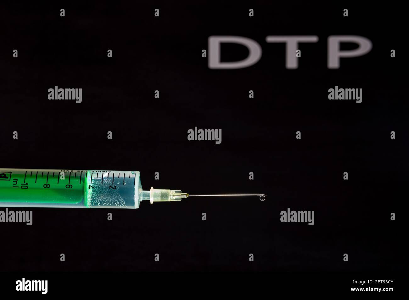 Cette photo montre une seringue jetable avec aiguille hypodermique, DTP écrit sur un tableau noir derrière Banque D'Images