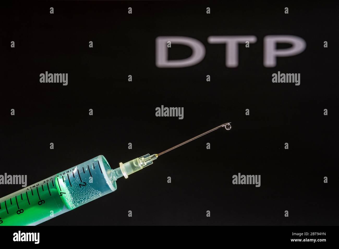 Cette photo montre une seringue jetable avec aiguille hypodermique, DTP écrit sur un tableau noir derrière Banque D'Images