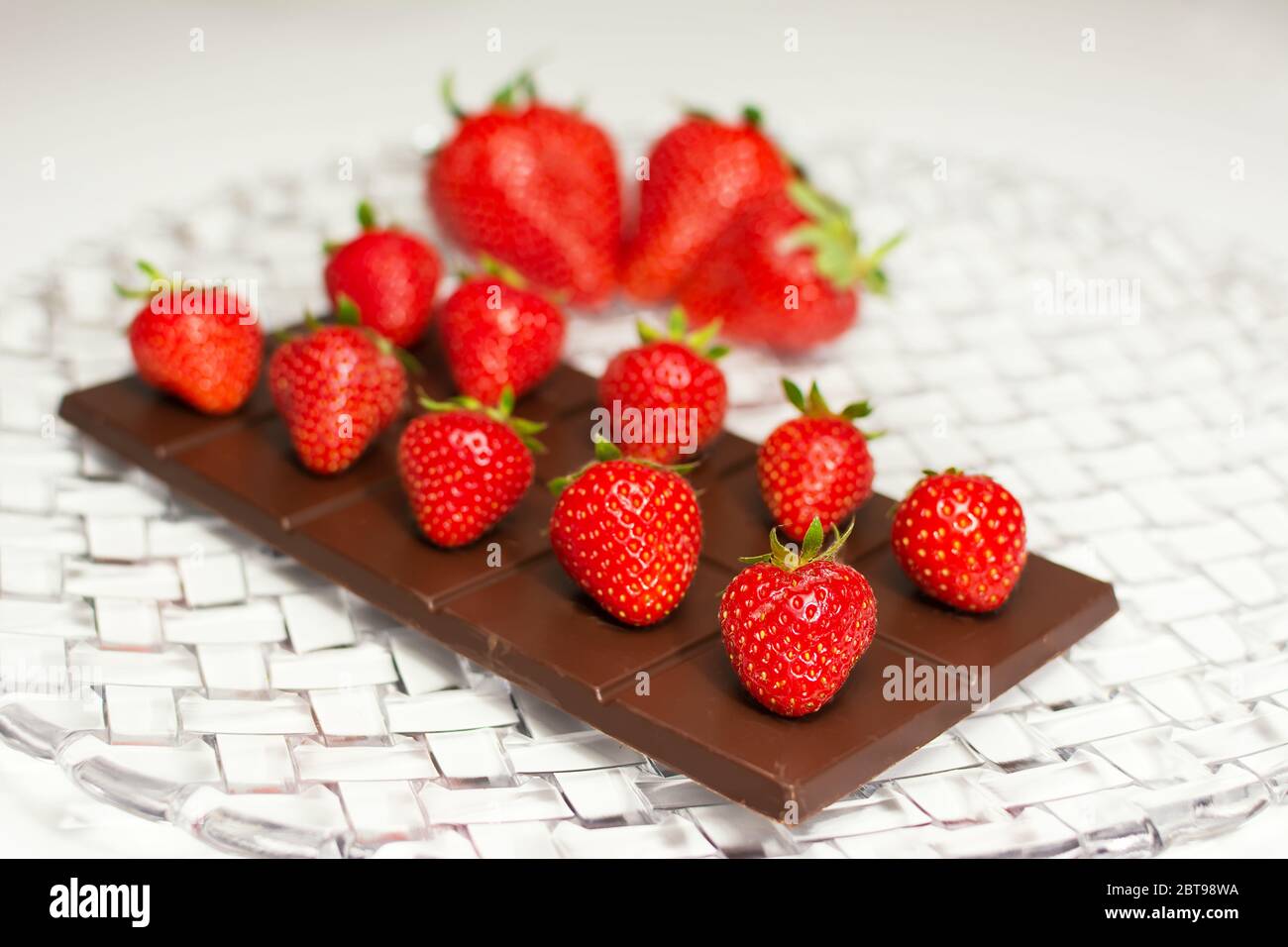 Une composition de plat avec un comprimé de Choccolate et des fraises sur le dessus et de grosses fraises floues en arrière-plan Banque D'Images