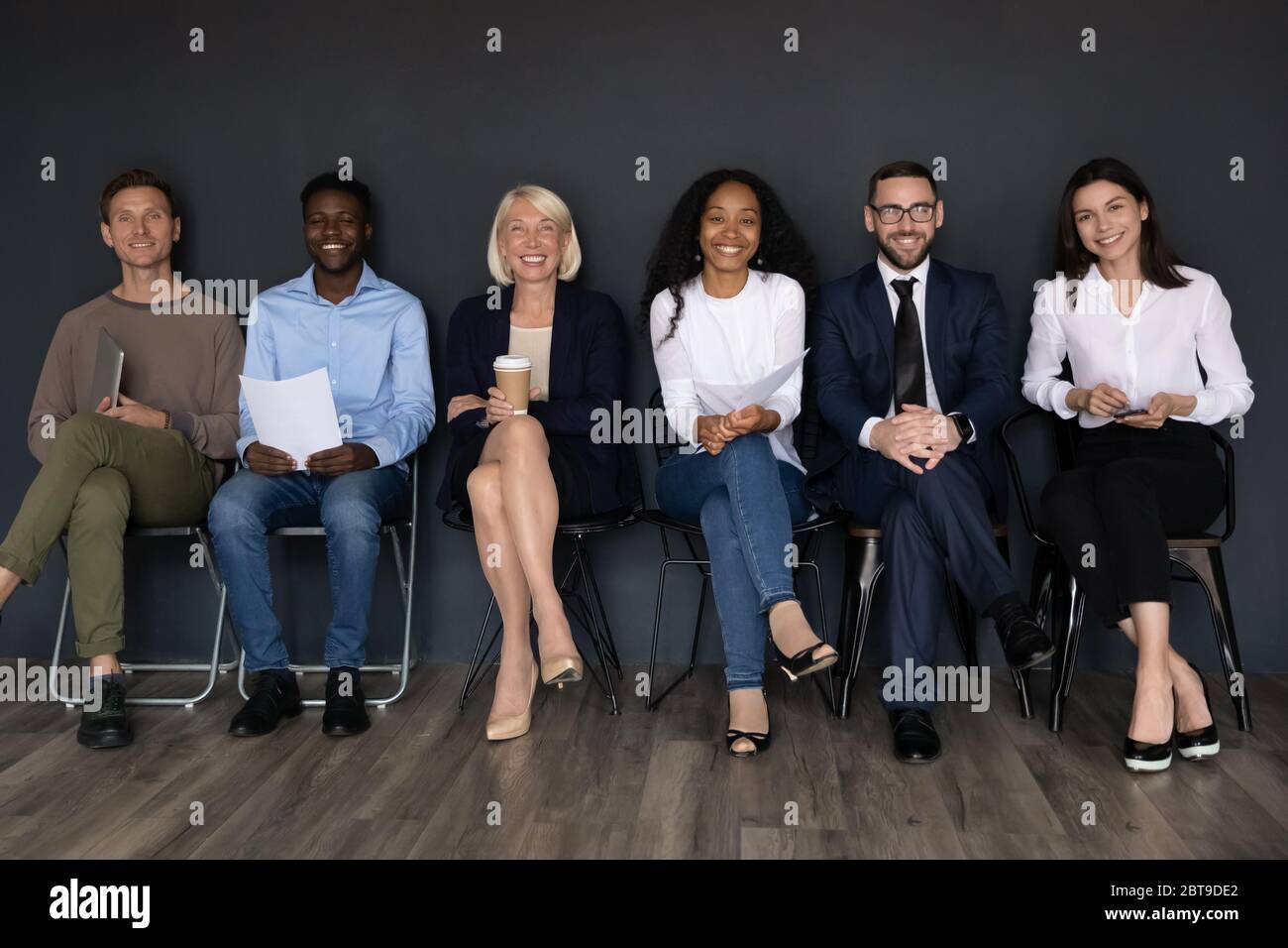 Portrait de groupe souriant des gens d'affaires assis sur des chaises dans la rangée Banque D'Images