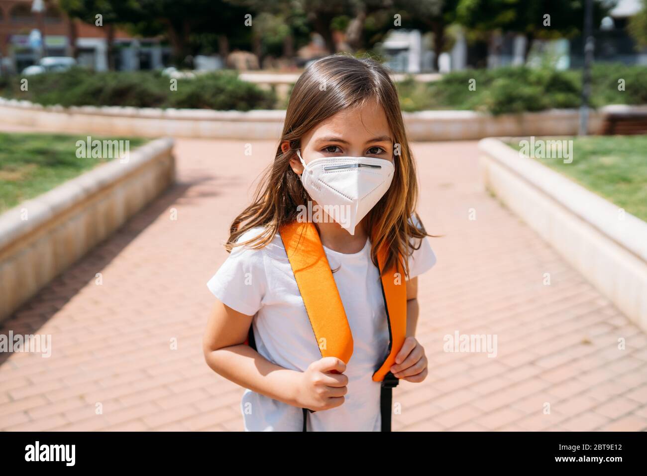 Petite fille avec masque dans un parc pendant la pandémie du coronavirus Banque D'Images