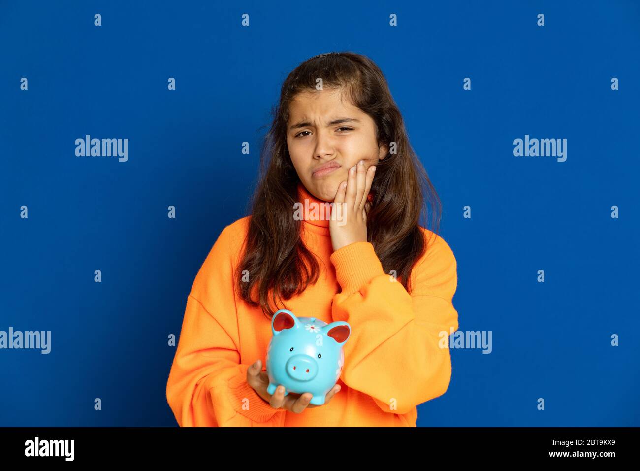 Adorable jeune fille de prètine avec jersey jaune sur fond bleu Banque D'Images