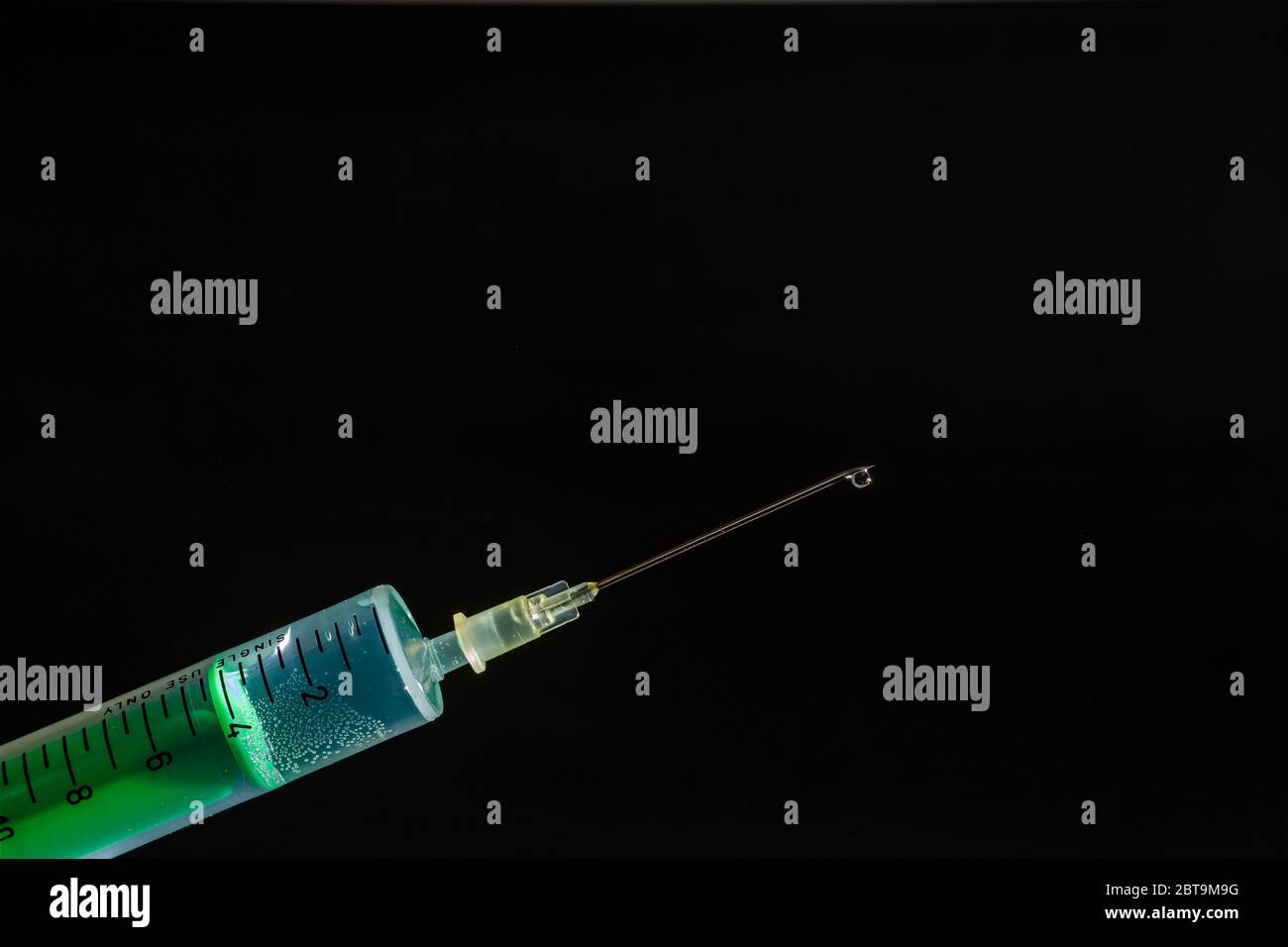 Cette photo montre une seringue jetable avec aiguille hypodermique, un panneau noir derrière Banque D'Images