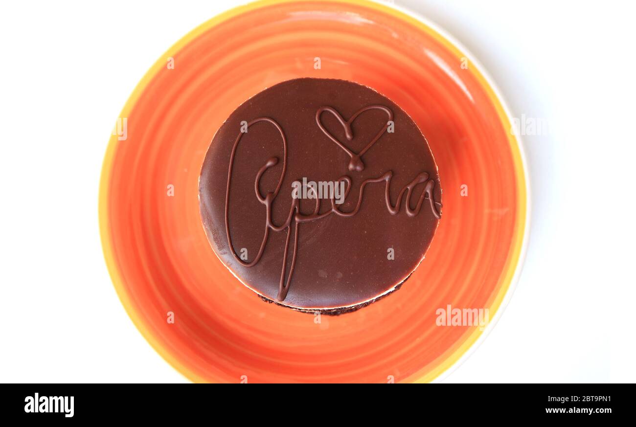 Vue de dessus de l'appétissant glaçage au chocolat d'un gâteau d'opéra rond sur une assiette d'orange vif Banque D'Images