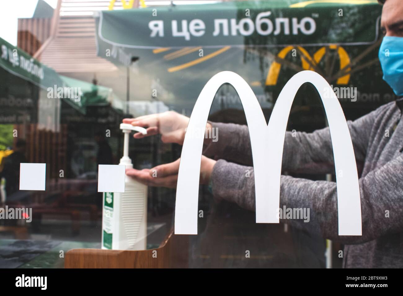 Lviv, Ukraine - Mai 17,2020 : homme utilisant un désinfectant antibactérien pour les mains dans McDonalds. Concept d'hygiène, prévention la propagation des germes dans les lieux publics et Banque D'Images